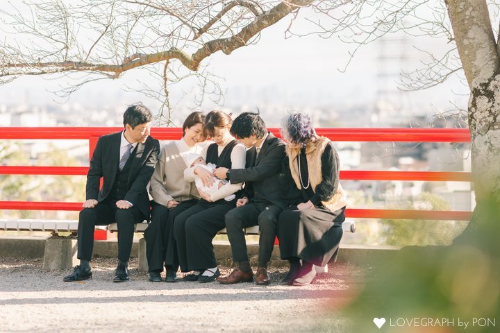 お宮参りで赤ちゃんを囲み、ベンチに座る参加者