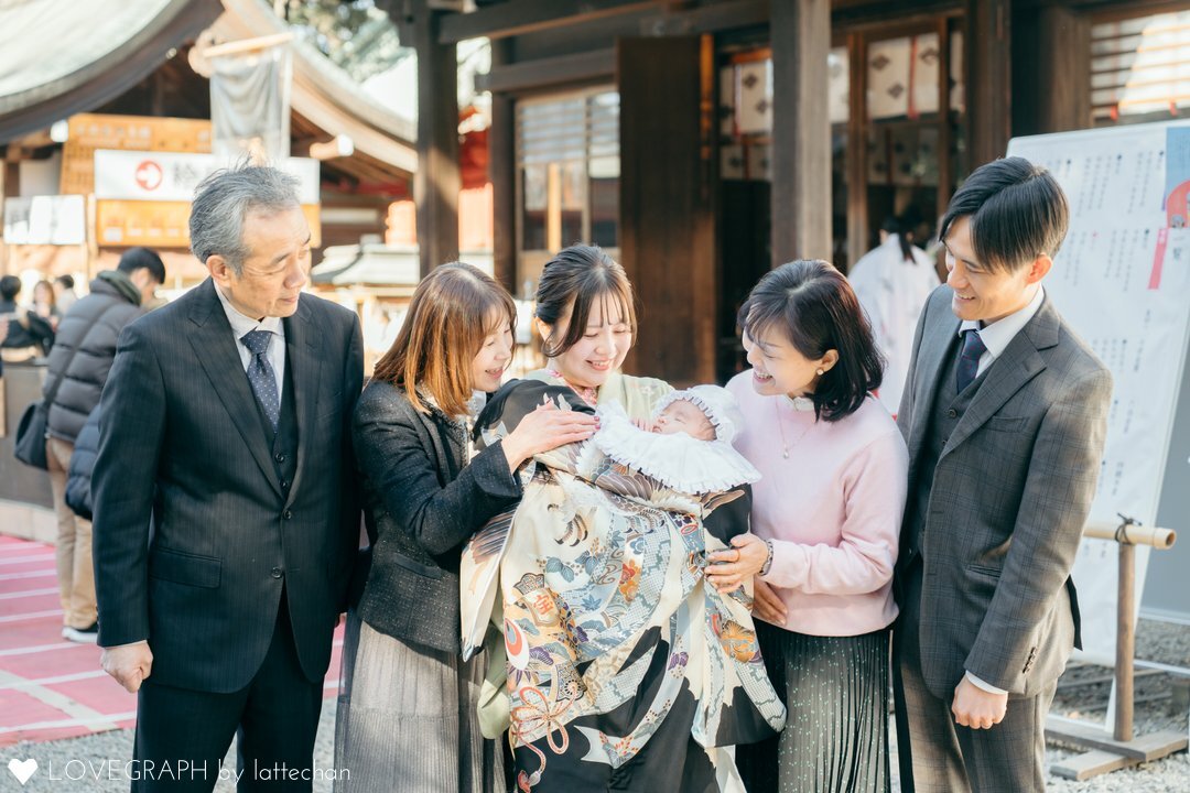 祖父母を含む家族で撮影したお宮参りの記念写真。祖父の服装はスーツ、祖母は黒いジャケットにグレーのスカート。