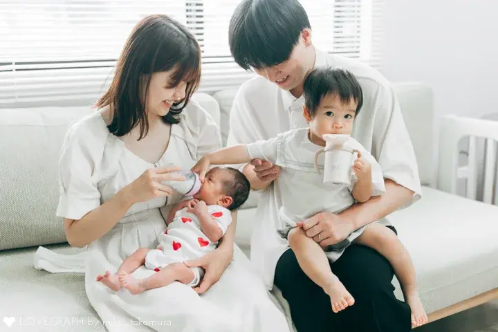 出張撮影だからこそ残せる家族4人全員の自然な姿。リビングでくつろぎながら、赤ちゃんの授乳を家族みんなで温かく見守る様子