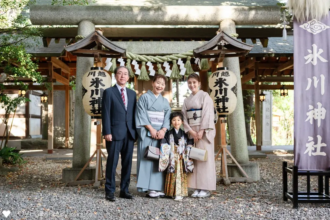 川越市護国神社前で、七五三の袴を着た男の子を囲んで笑顔で並ぶご家族4人（祖父、祖母、母、男の子）の記念写真。