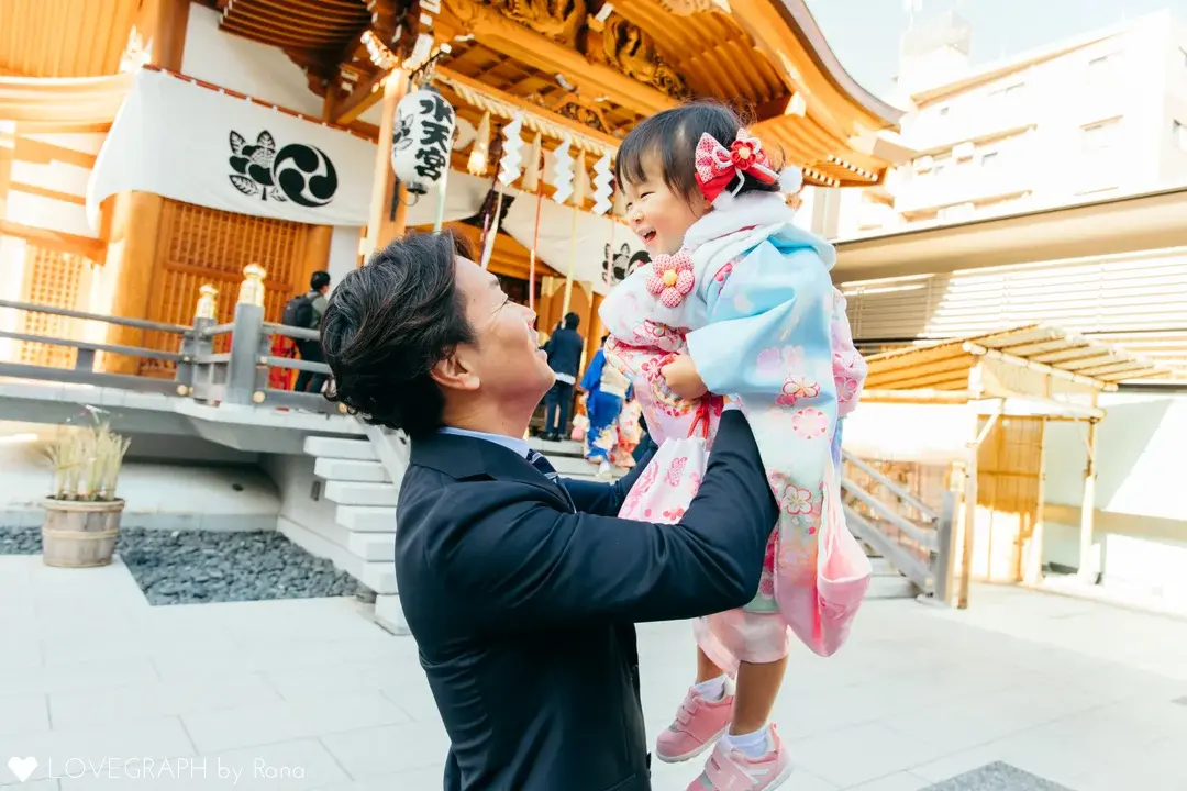 東京水天宮を背景に撮影した着物を着た七五三の3歳女の子を抱き抱えるスーツ姿の父親の写真
